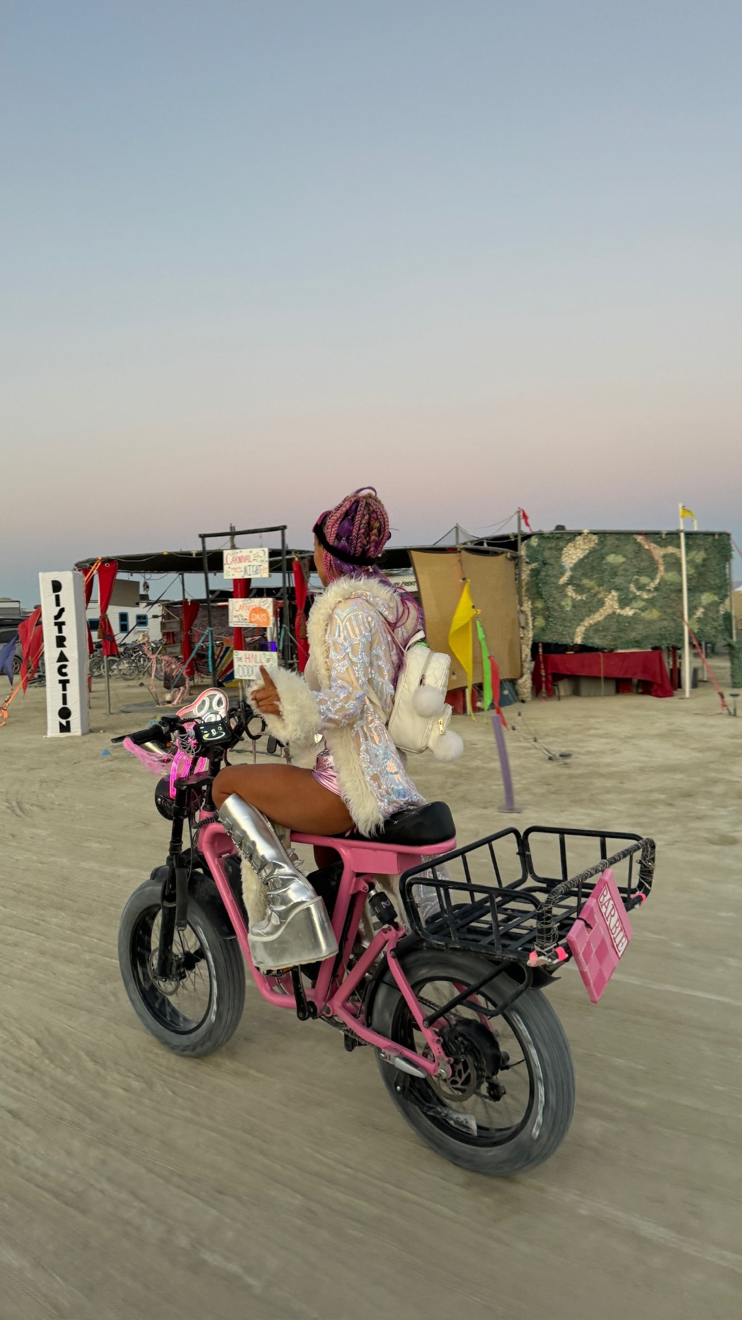 Rider in sequined jacket and silver boots on a Hot Pink DUST eBike at dusk in the desert