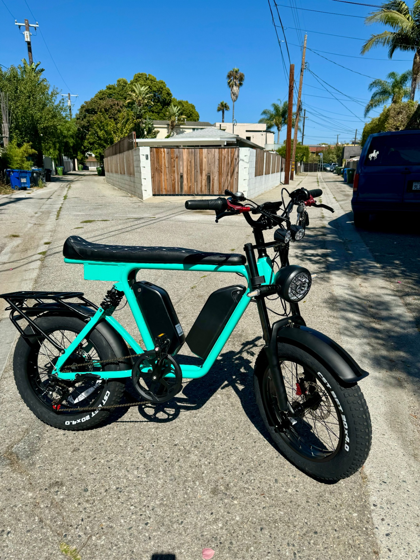 Teal DUST eBike parked in a sunlit palm-lined alley in Southern California